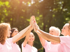  Women in pink shirts joining hands to promote breast cancer awareness 