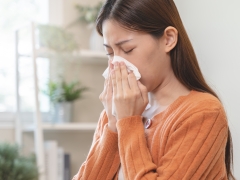  A woman with a cold, covering her sneeze. 