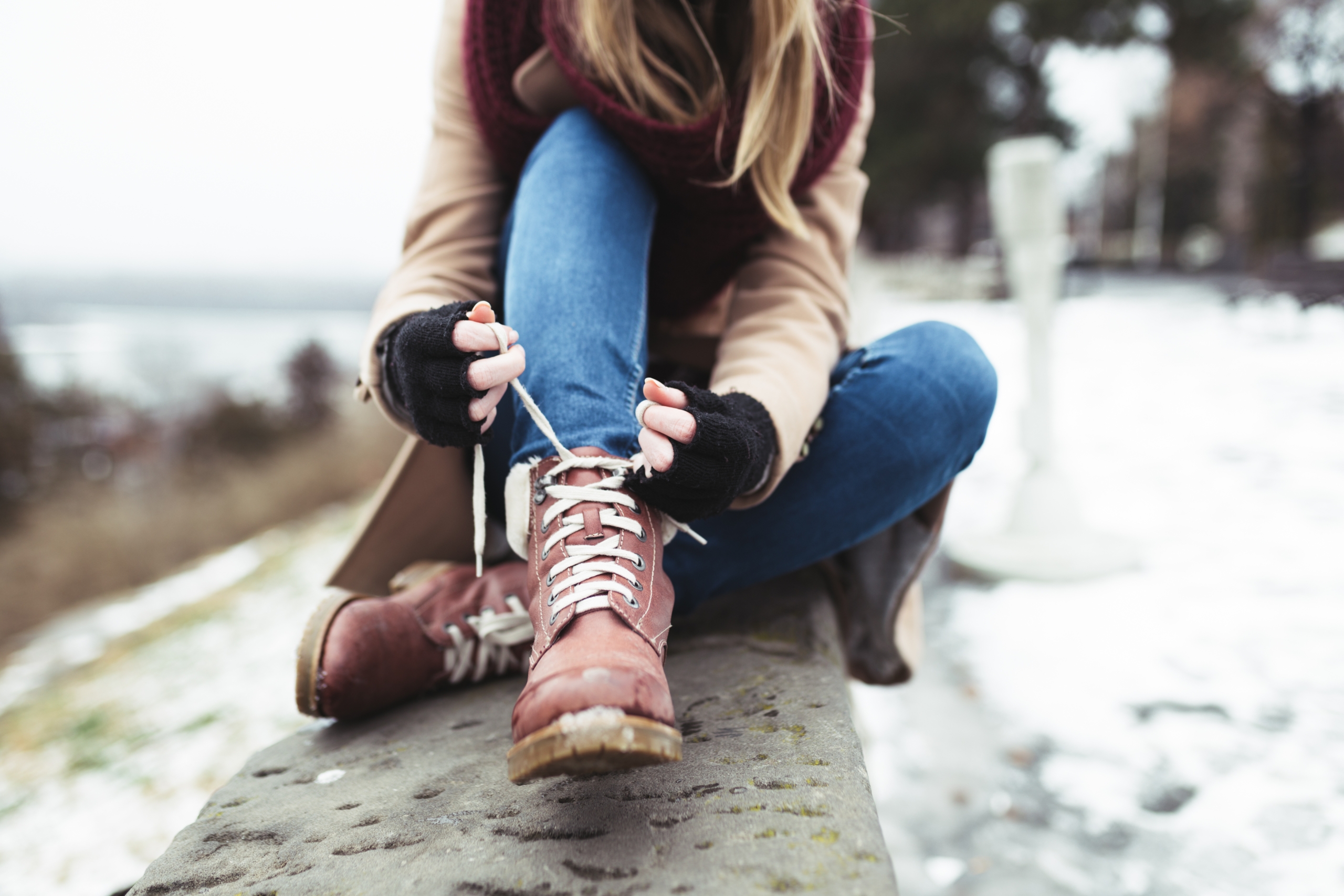 A woman tying up a pair of winter boots.