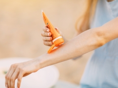  Young woman applying sunscreen. 